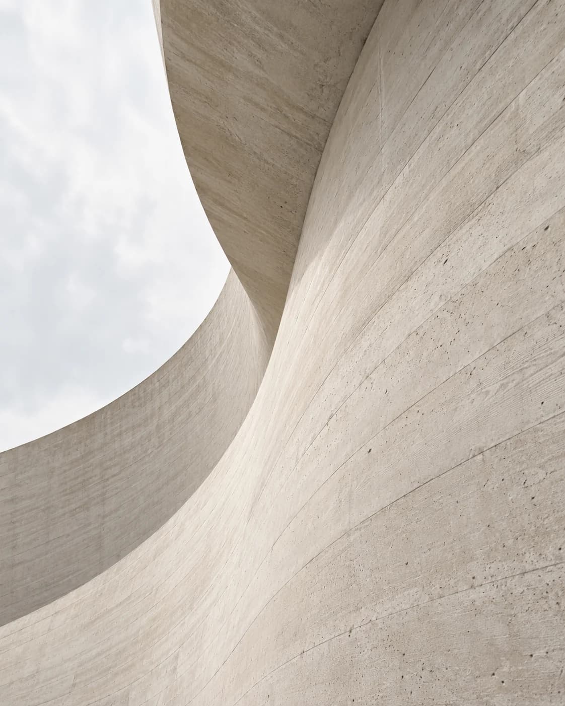 Abstract view of a sweeping curved concrete wall seen from below.